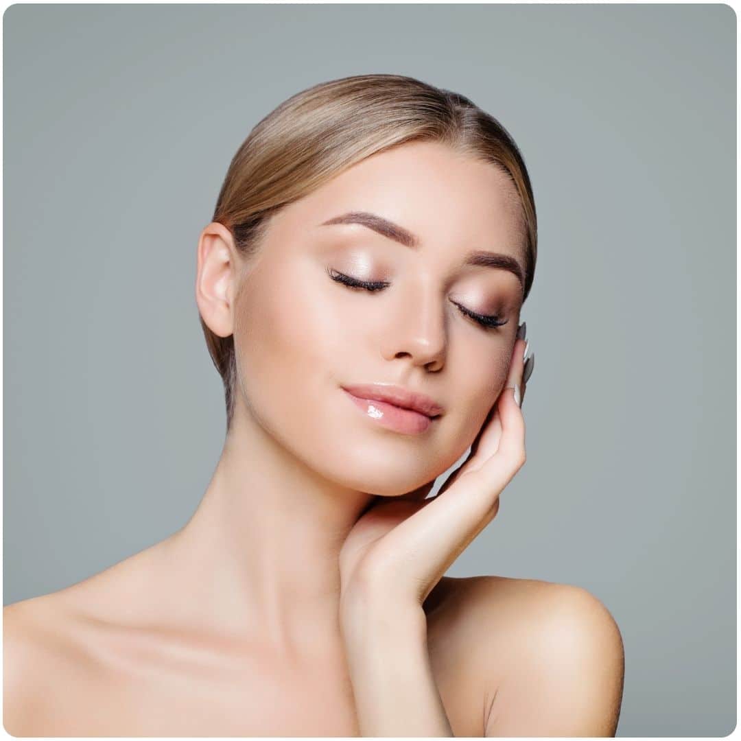 a woman smiling and touching her cheek