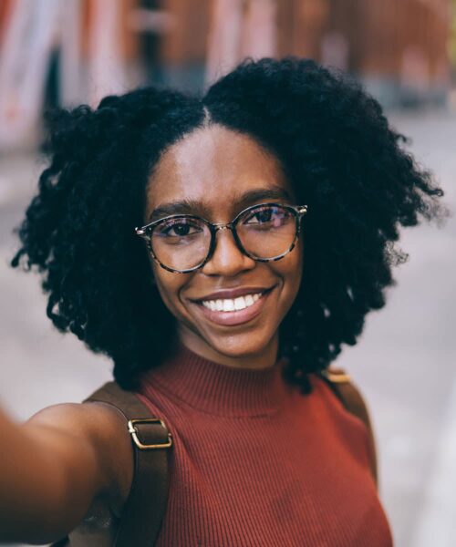 A Person Wearing Glasses And Smiling At The Camera